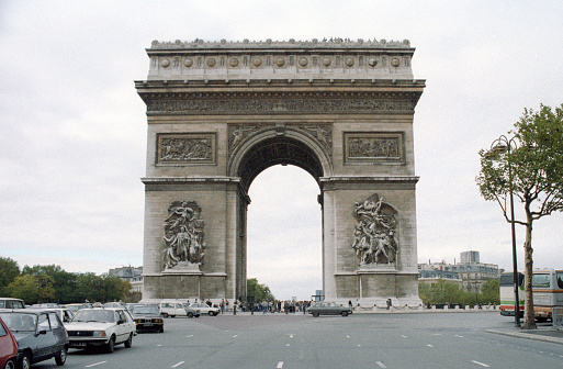 Paris, France - 1983: A vintage 1980's Fujifilm negative film scan of the Arc de Triomphe in Paris with traffic on the roundabout roadway.