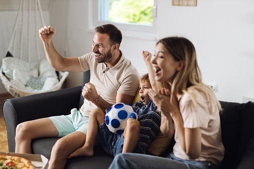 Cheerful family celebrating the victory of their soccer team at home