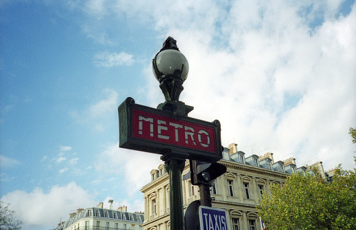 Paris, France - 1983: A vintage 1980's Fujifilm negative film scan of the classic ornate Paris Metro station sign and street lamp.