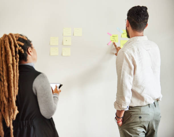 istock Young colleagues brainstorming with sticky notes in their start up's home office 1421659744