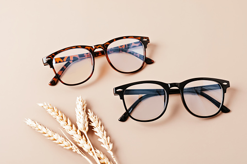Stylish eyeglasses over pastel background. Optical store, glasses selection, eye test, vision examination at optician, fashion accessories concept. Top view, flat lay