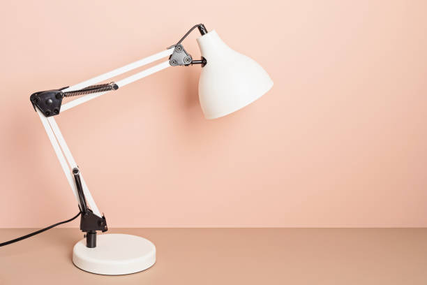 istock Table lamp over pink background with copy space. Reading, studying, office space concept 1421660861