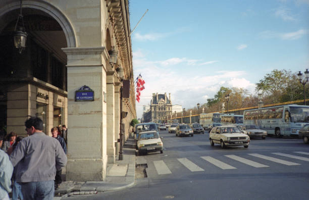 Paris, France - 1983: A vintage 1980's Fujifilm negative film scan of streets and buildings in central Paris, France with cars and pedestrians traveling.