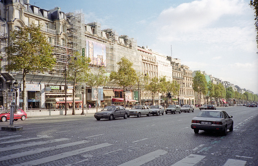 Paris, France - 1983: A vintage 1980's Fujifilm negative film scan of cars traveling down the  avenue des Champs Elysees in Paris, France.