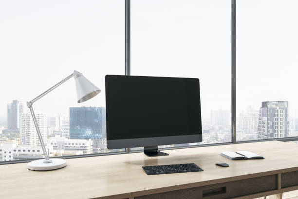 istock Close up of empty computer display on wooden office desktop with objects, lamp and supplies on panoramic window and city view background. Mock up, 3D Rendering. 1421664044