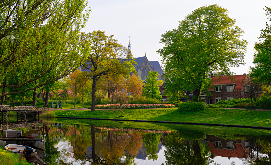 he big Saint-Laurens church during Spring in the historic city centre of Alkmaar, the Netherlands, with its reflection in a canal, Singel, in the foreground. The small bridge is also a sluice.