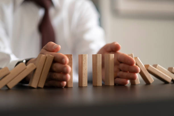 istock Businessman Stop Domino Effect. Risk Management and Insurance Concept 1421668112