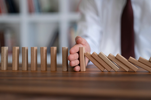 Businessman Stop Domino Effect. Risk Management and Insurance Concept