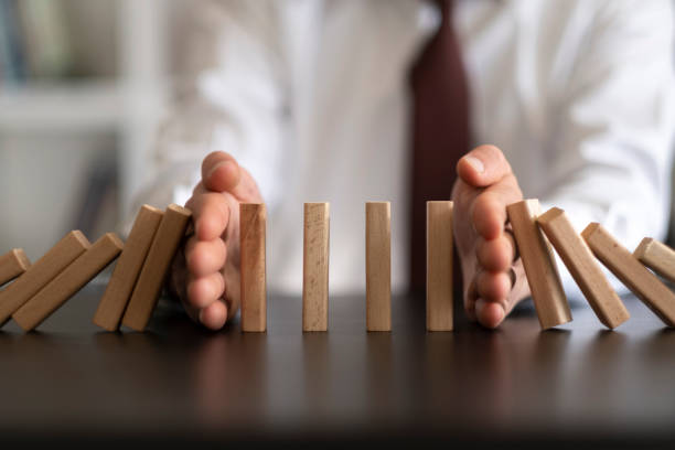 businessman stop domino effect. risk management and insurance concept - bescherming stockfoto's en -beelden