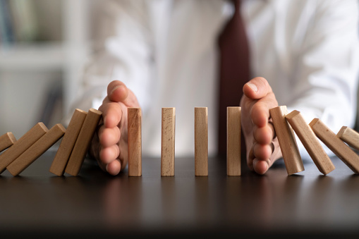 Businessman Stop Domino Effect. Risk Management and Insurance Concept