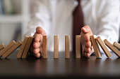 Businessman Stop Domino Effect. Risk Management and Insurance Concept