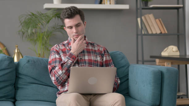 man with laptop thinking on sofa - 32457 imagens e fotografias de stock