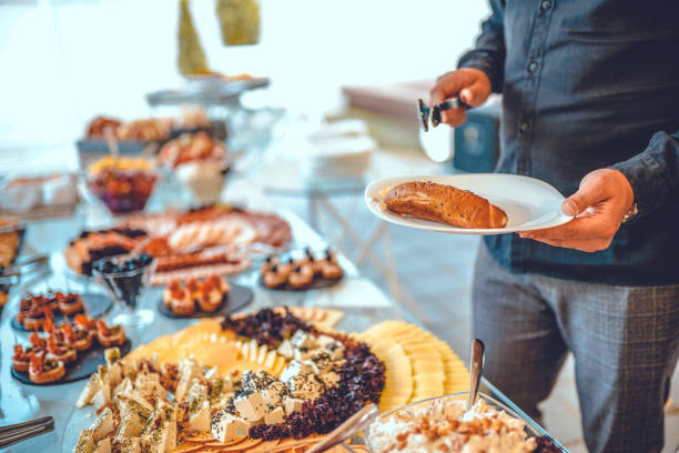 istock Man holding plate and taking food from buffet table during breakfast in hotel 1421670795