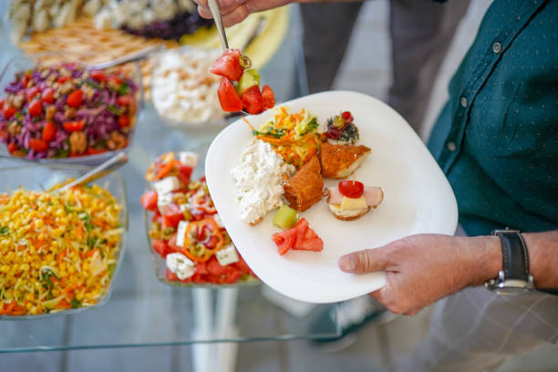 istock Man holding plate and taking food from buffet table during breakfast in hotel 1421672039