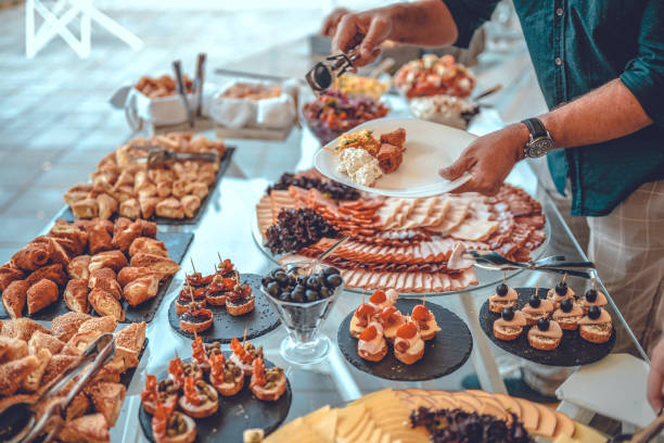 istock Man holding plate and taking food from buffet table during breakfast in hotel 1421672057