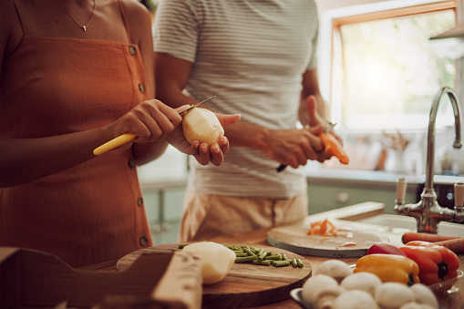 Healthy, diet and food of a couple preparing or making a meal together for lunch in the kitchen at home. Caring and loving man and woman in a relationship working as a team for support.