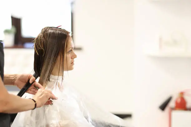 Hairdresser hands cut hair of client in beauty salon. Classic version of bob haircut technology