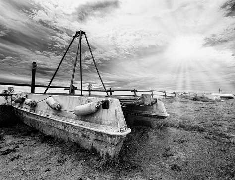 rotting fishing boat abandoned on the shore long exposure black and white