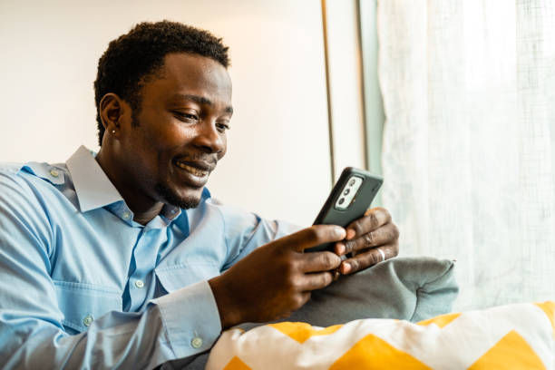 istock A man holding a smart phone on blue couch. 1421682276