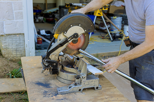 The worker is using a miter saw to cut the iron metal pipe with splashes of sparks