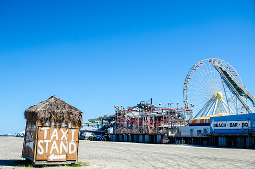 Closed taxi stand on Wildwood beach with amusement park in background during summer day