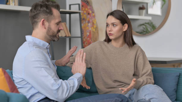 istock Serious Man Talking to Woman While Sitting on Sofa 1421685053