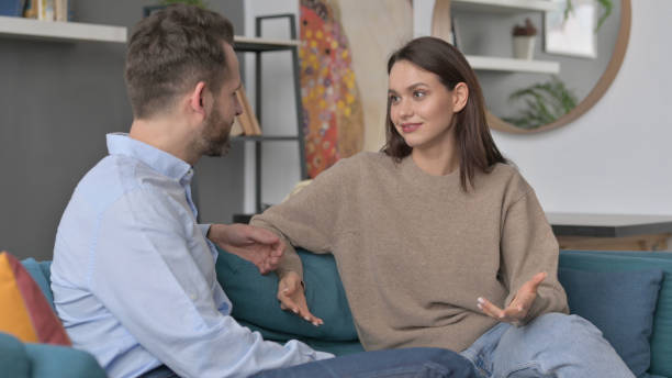 istock Serious Woman Talking to Man While Sitting on Sofa 1421685722