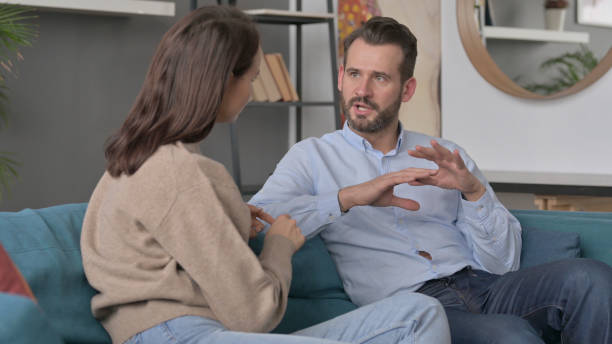 istock Serious Man Talking to Woman While Sitting on Sofa 1421686232