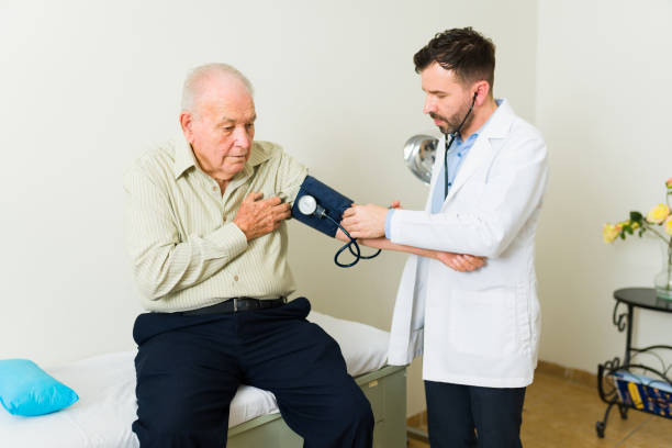 homme âgé souffrant d’hypertension artérielle se faisant examiner par un médecin - blood pressure gauge medical exam healthcare and medicine equipment photos et images de collection