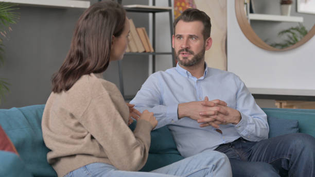 istock Serious Man Talking to Woman While Sitting on Sofa 1421686460
