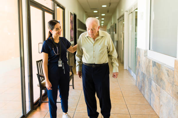 istock Happy old man using a walker and latin nurse at the retirement home taking a walk 1421686989