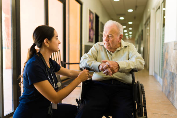 Caring nurse chatting with a disabled old man stock photo