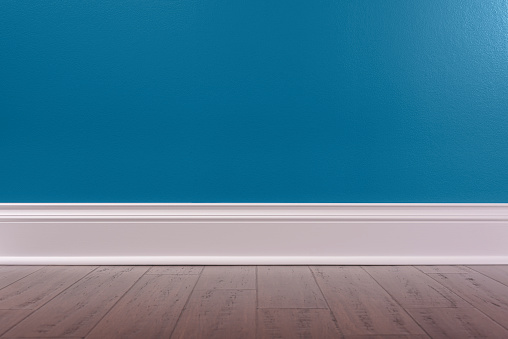 An Empty room background with a dark blue wall, white baseboard and rustic wooden floor.