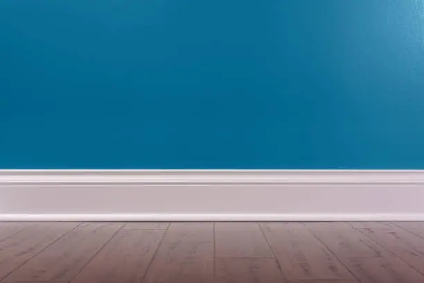 An Empty room background with a dark blue wall, white baseboard and rustic wooden floor.