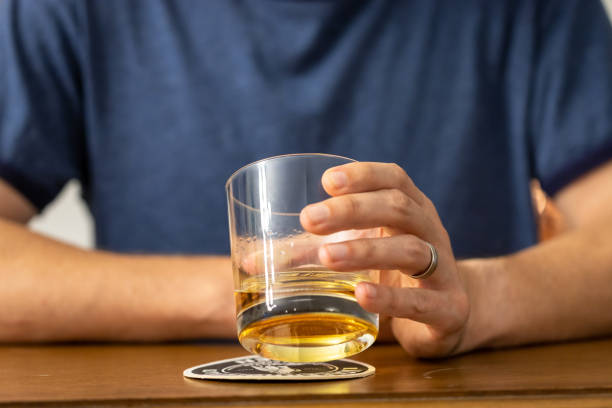 uomo che beve un bicchiere di whisky in un bar - alcolismo foto e immagini stock