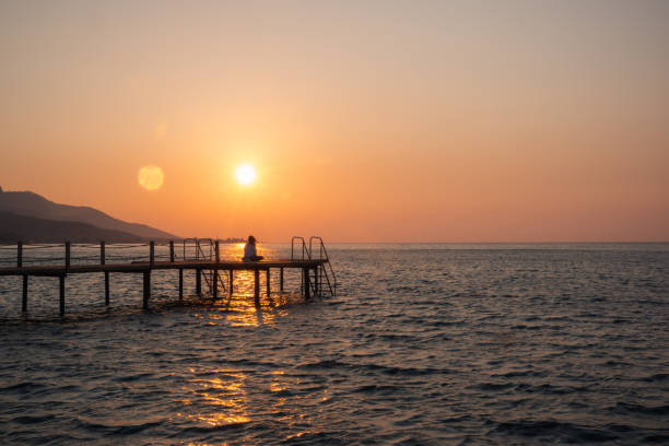 istock Woman practicing yoga alone on a pier at sunrise 1421693685