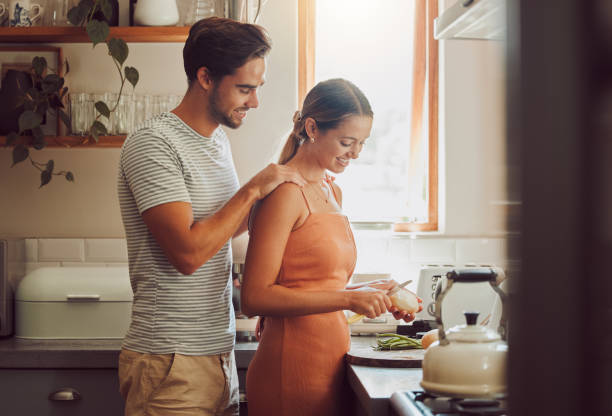 istock Romantic, caring and loving young couple supporting each other while preparing a meal in the kitchen. Man and woman in a happy, stressless and relaxed relationship together cooking at home. 1421693741