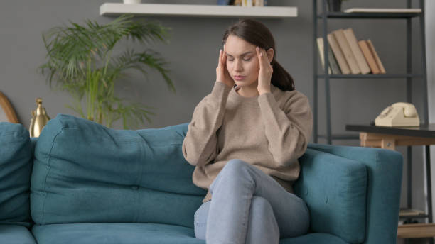 istock Woman having Headache while Sitting on Sofa 1421694360