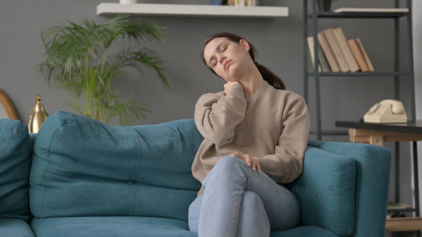 istock Woman having Neck Pain while Sitting on Sofa 1421695008