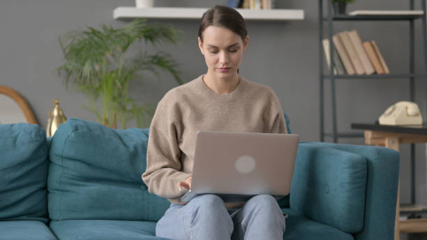istock Woman Working on Laptop on Sofa 1421697901