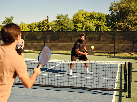 A group of young adults playing Pickleball at a public court.