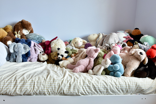 Too many toys on bed, needing organization solution. Cute kid's bedroom and stuffed toys