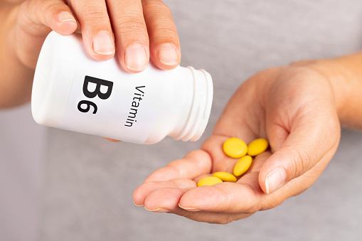 Woman hand takes vitamin B6  from medicine container