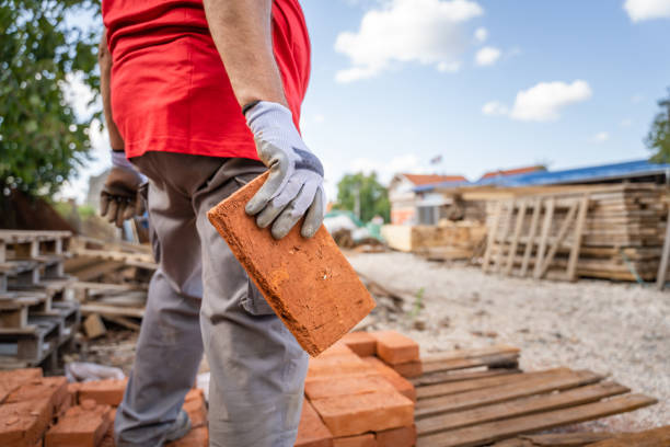 midsection of unknown caucasian man male construction or warehouse worker carry or hold clay bricks while stand outdoor in sunny day copy space