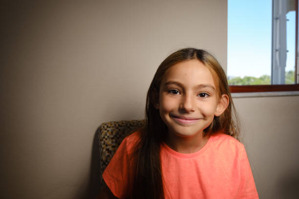 11 year old girl with straight long hair. Smiling face.Portrait,model looking at camera.High strength to live hopeful.Space for text.İn the house.