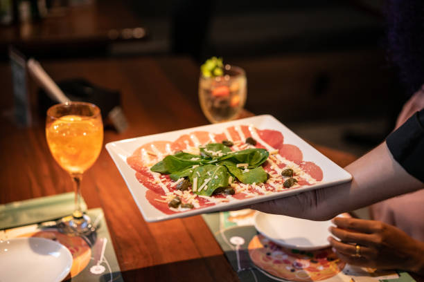 istock Waiter serving carpaccio at restaurant 1421725561