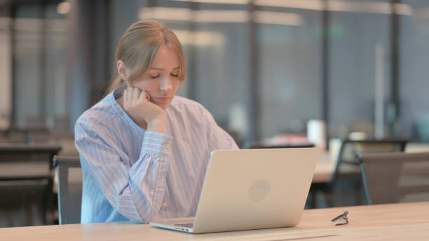 istock Tired Young Woman taking Nap While Sitting in Office with Laptop 1421726518