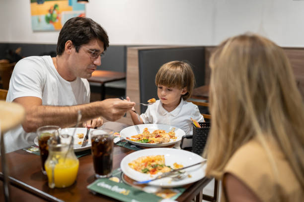 istock Father helping son eat pizza 1421727264