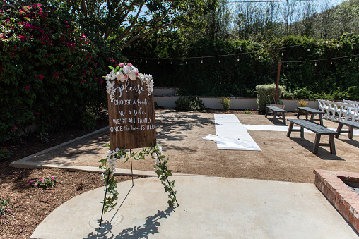 Wedding ceremony sign shows all inclusive seating assignment with freedom to sit on either side of the isle.