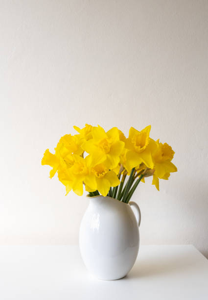 istock Vertical closeup of daffodils in white vase 1421735745